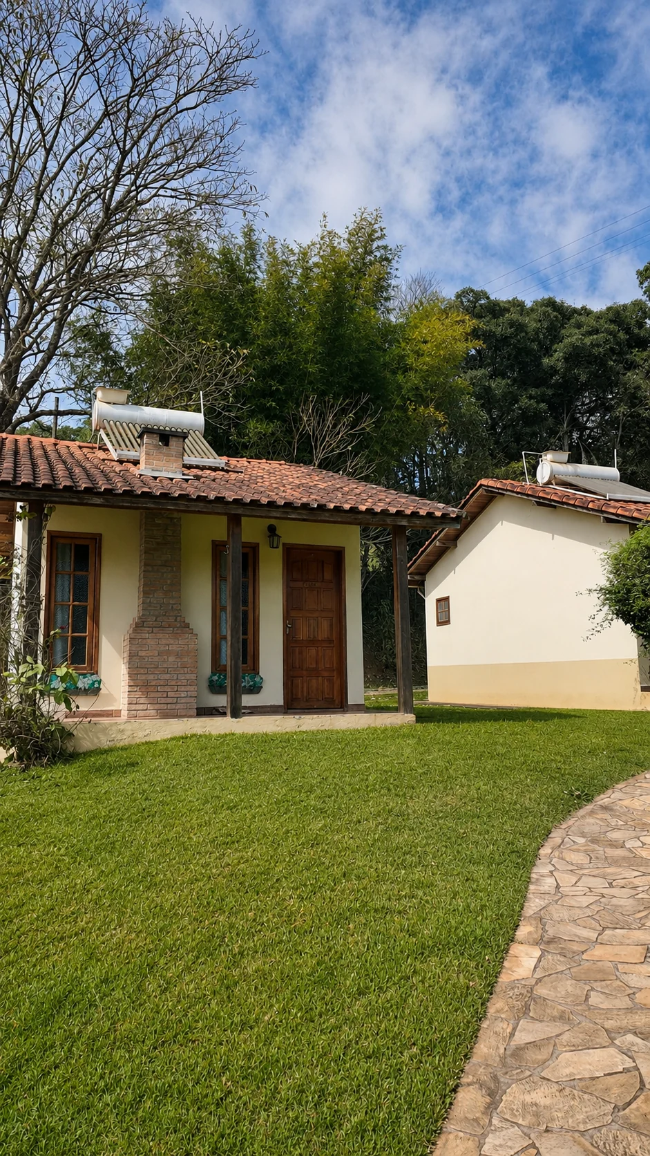 Chalés entre o gramado, as árvores e o caminho de pedra da pousada