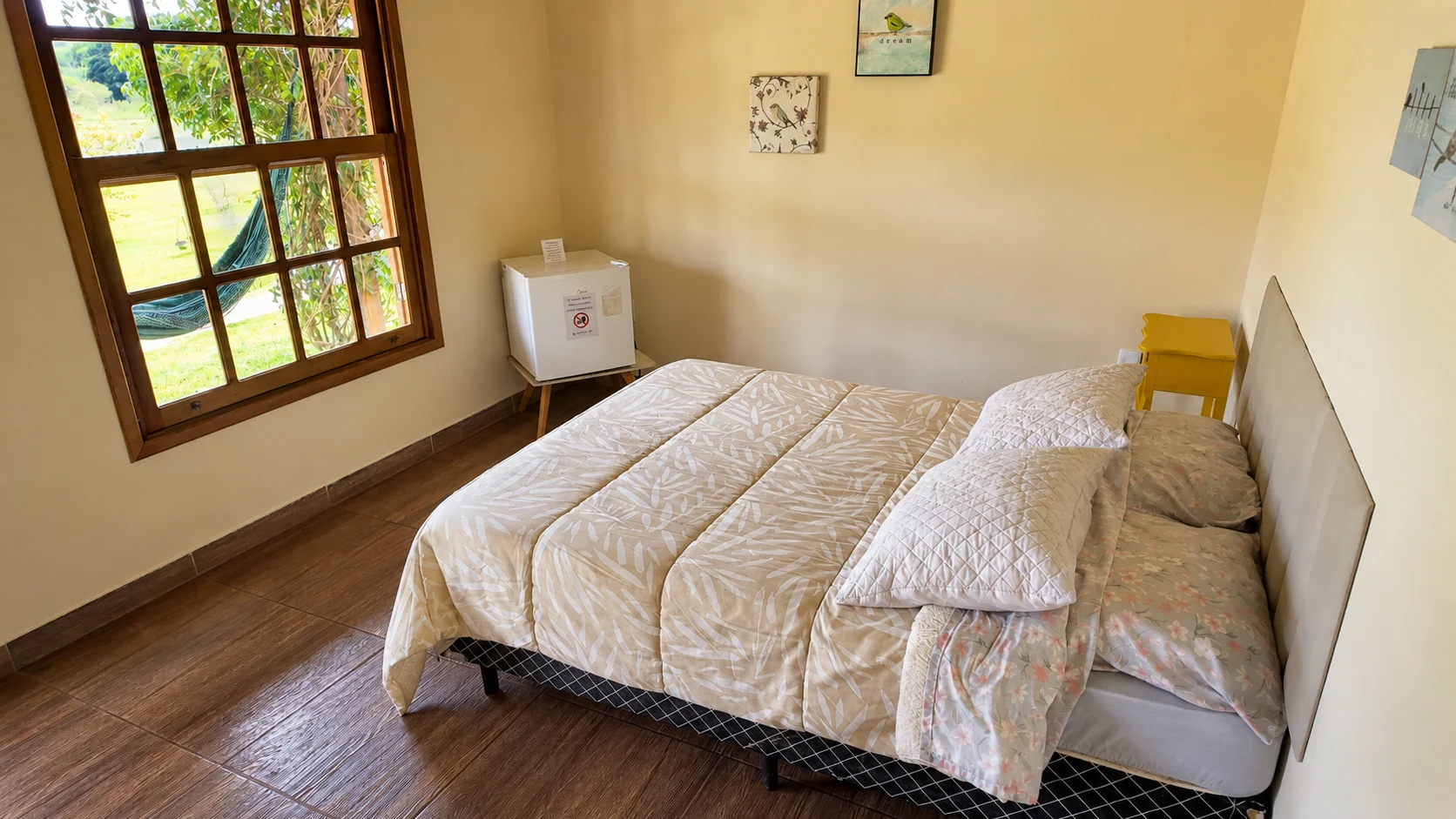Cama arrumada em quarto de chalé com luz natural