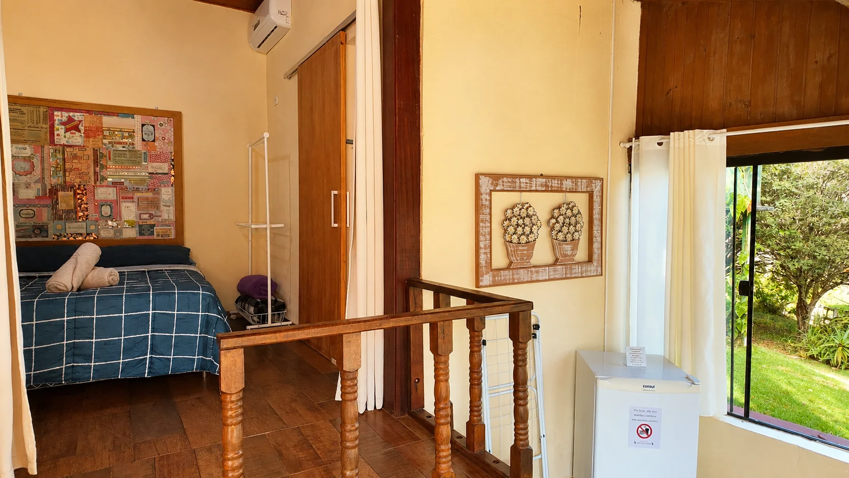 Quarto de chalé com cama azul e porta aberta para o verde
